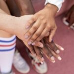 Player Community - Faceless multiracial sport team stacking hands on court