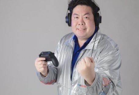 Game Endings - A man in a silver jacket holding a video game controller